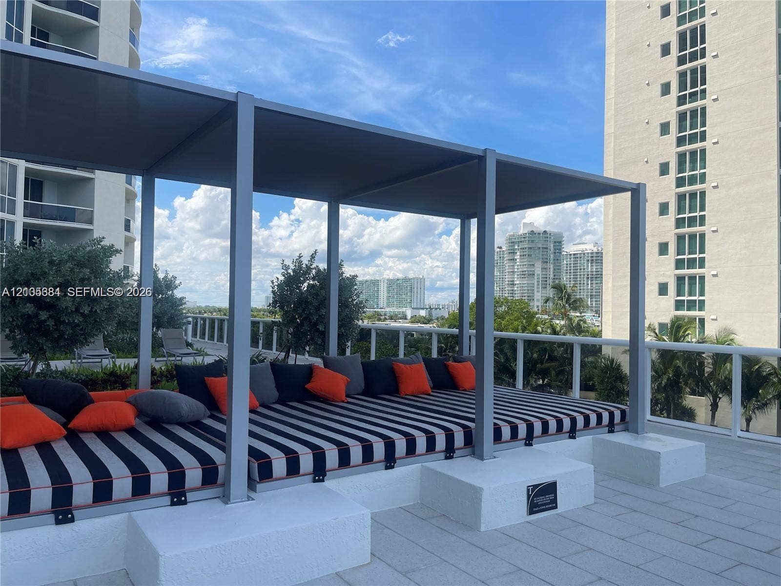 16001 Collins Avenue, #2803, Sunny Isles Beach, Sunny Isles Beach, FL 33160 Rooftop terrace featuring a covered lounge area, glass panel railings, and urban skyline backdrop