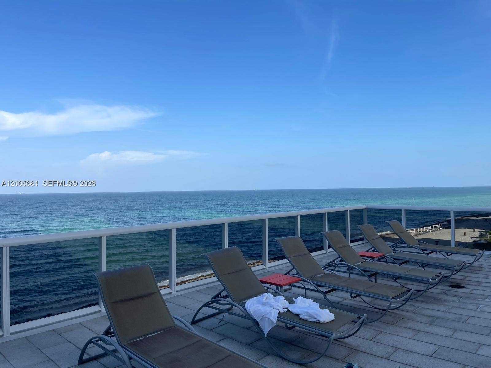 16001 Collins Avenue, #2803, Sunny Isles Beach, Sunny Isles Beach, FL 33160 Oceanfront deck with multiple lounge chairs, composite decking, and metal railings overlooking pristine waters and clear blue skies