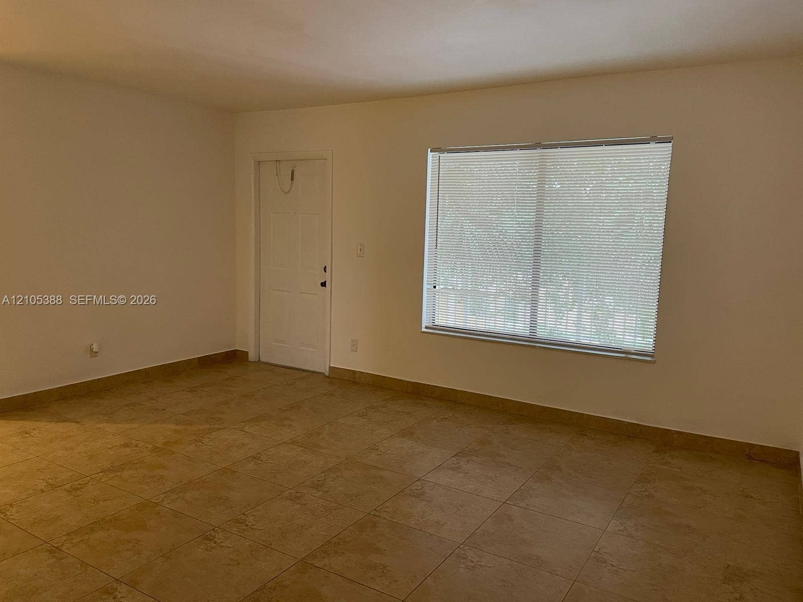 Neutral wall paint, tile flooring, and a window with blinds