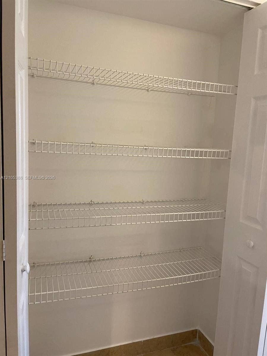 Bi-fold doors reveal a closet with white wire shelving and a tiled floor