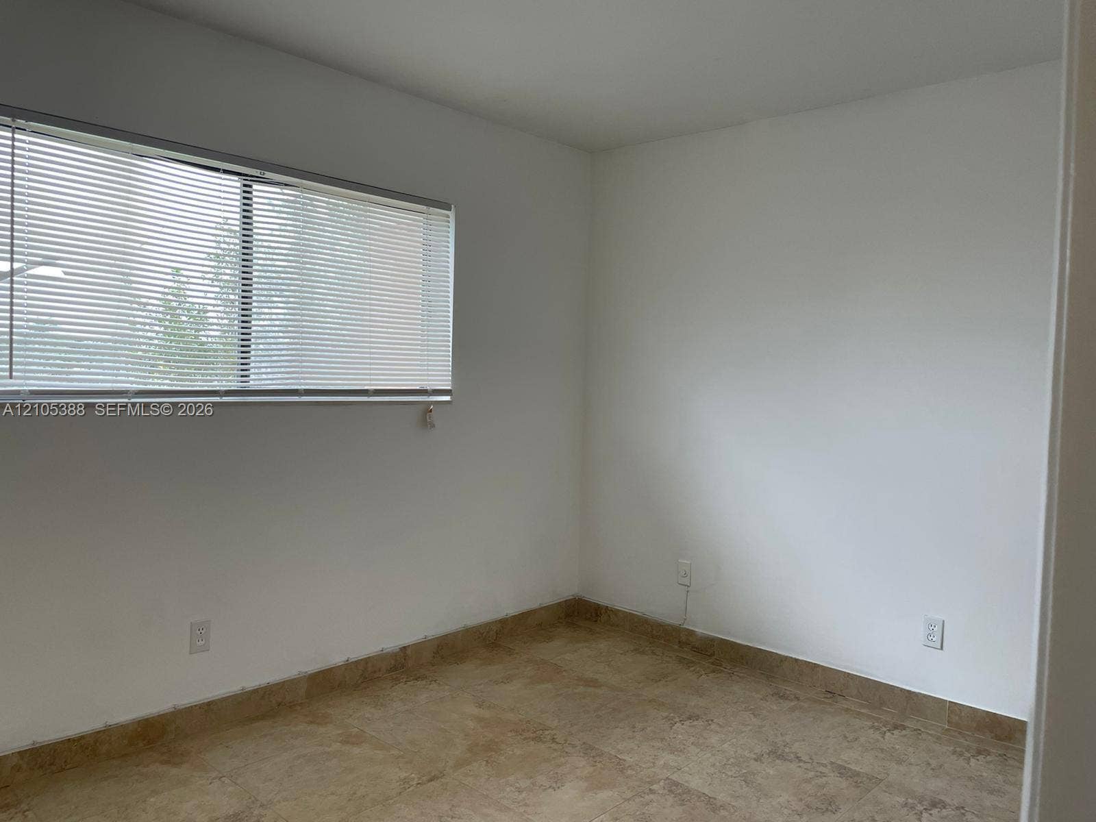 Rectangular window with horizontal blinds, neutral wall paint, and tile flooring