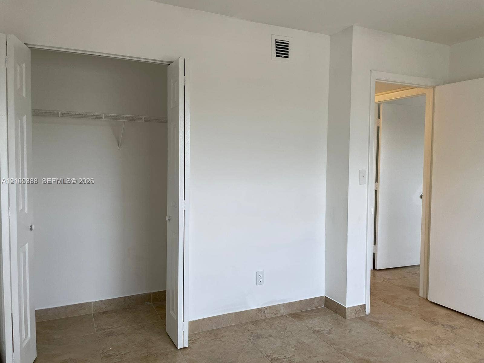 Neutral wall finishes, bi-fold closet doors, wire shelving, and tiled flooring