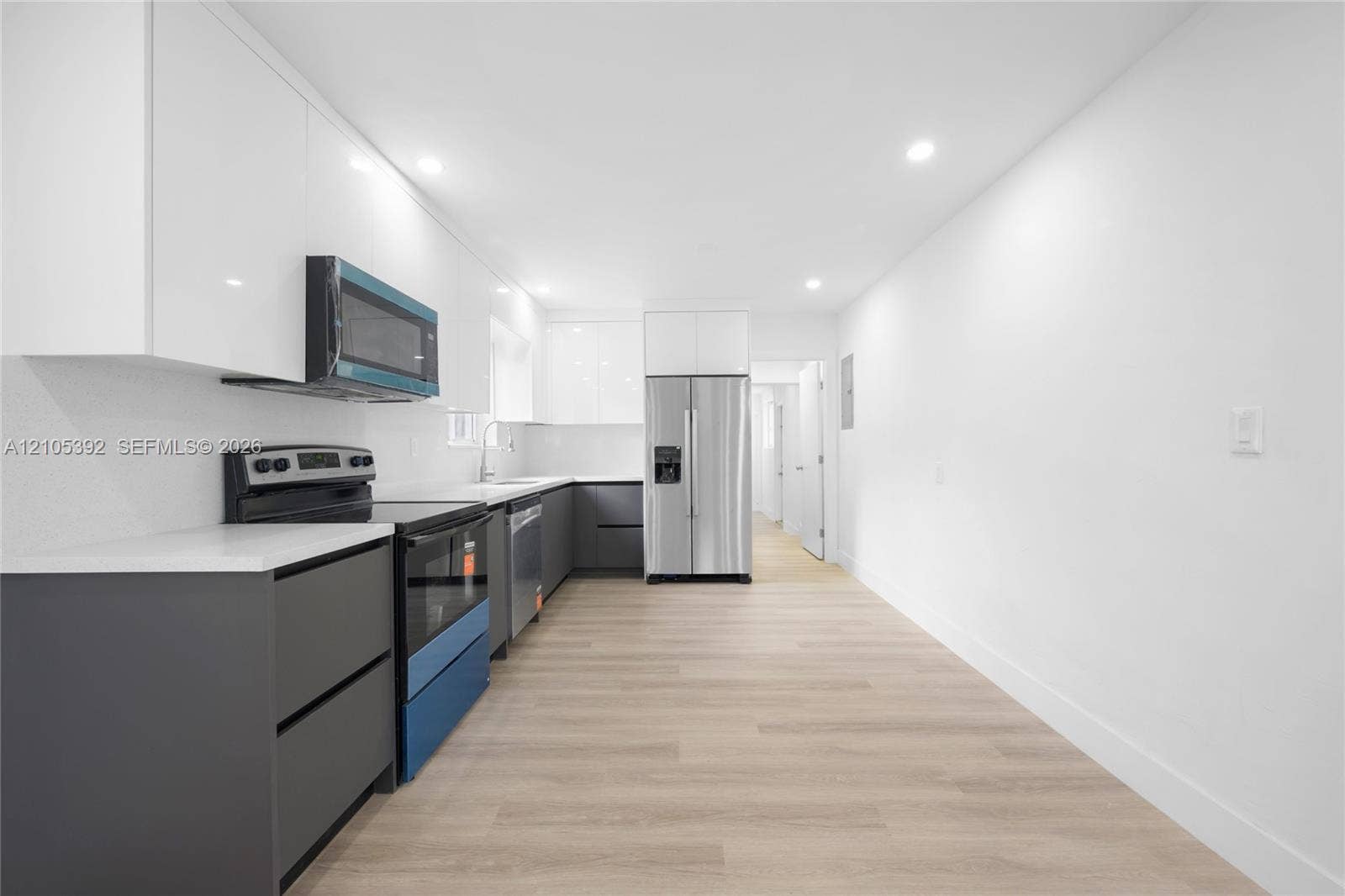 3197 Cleveland Street, Hollywood, FL 33021 Modern kitchen featuring white upper cabinetry, grey lower cabinetry, light-toned wood-finish flooring, recessed lighting, and stainless steel appliances