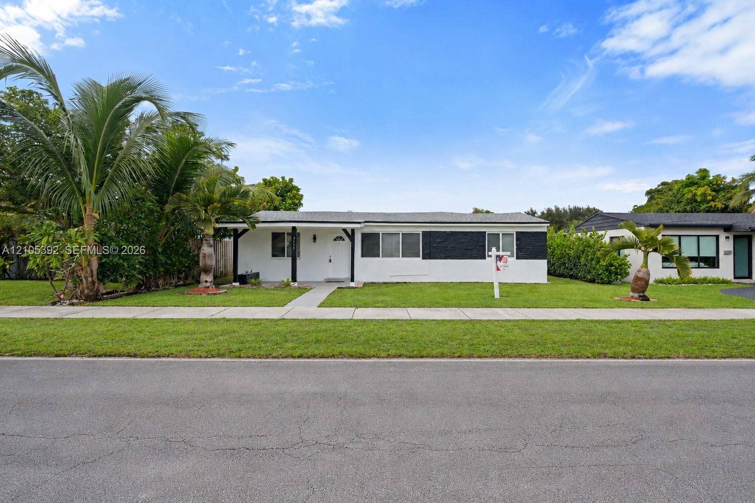 3197 Cleveland Street, Hollywood, FL 33021 White exterior with black accents, covered entry, and a level lawn