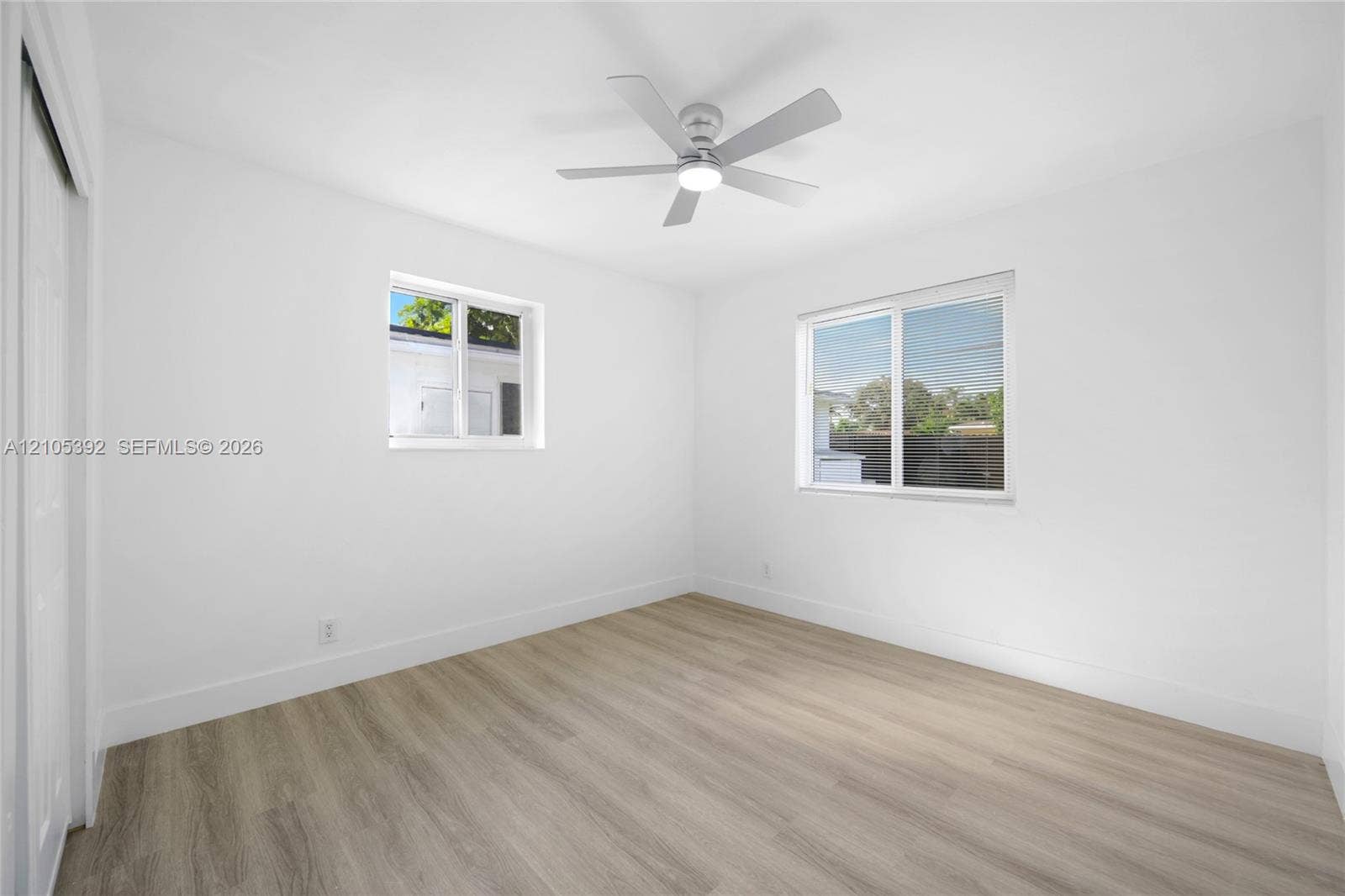 3197 Cleveland Street, Hollywood, FL 33021 Wood-finish flooring, white walls, two windows with white frames, a ceiling fan with integrated lighting, and a white sliding closet door