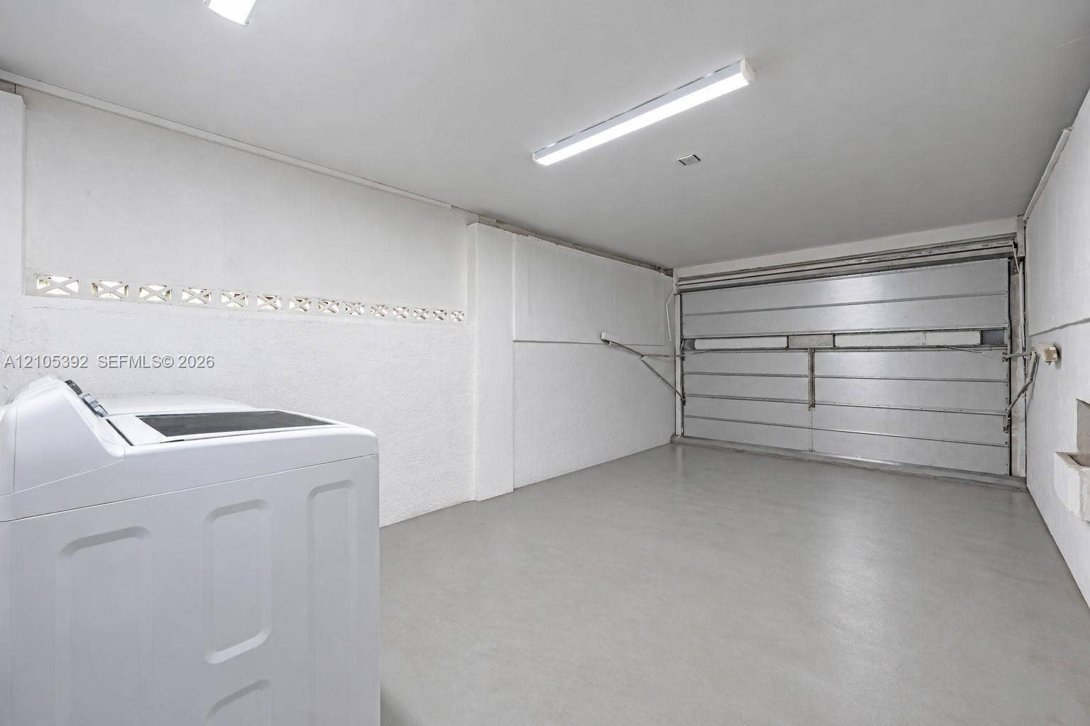 3197 Cleveland Street, Hollywood, FL 33021 White walls, concrete flooring, fluorescent lighting, and a metal roll-up door