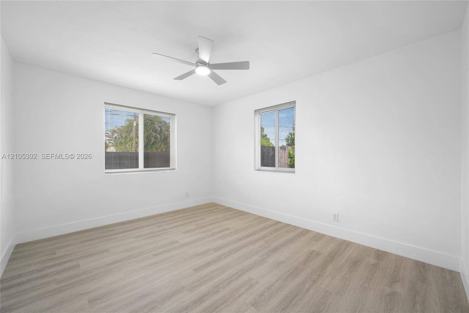 3197 Cleveland Street, Hollywood, FL 33021 Bright interior with wood-finish flooring, two large windows, a ceiling fan with integrated lighting, and crisp white walls