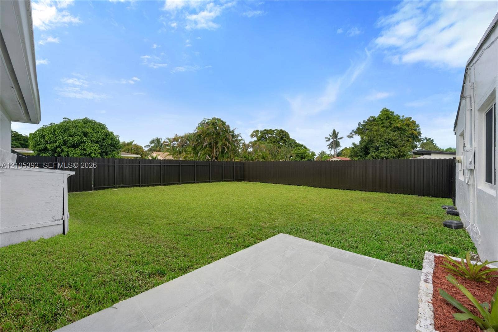 3197 Cleveland Street, Hollywood, FL 33021 Expansive backyard featuring a large grass area, dark perimeter fencing, and a concrete patio