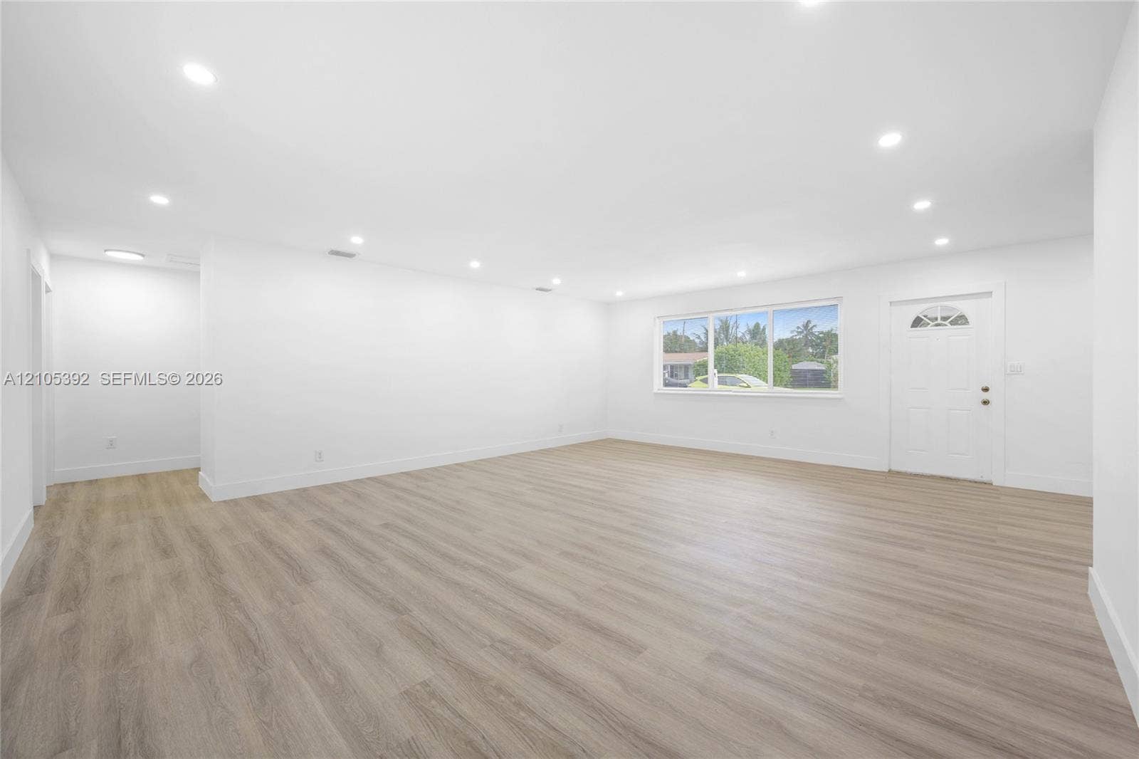 3197 Cleveland Street, Hollywood, FL 33021 Expansive living area with wood-finish flooring, recessed lighting, large window, and white entry door with decorative glass insert