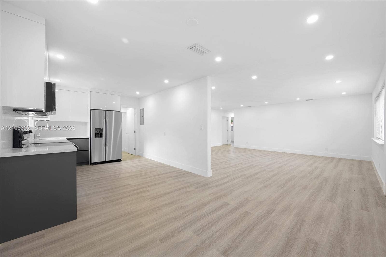 3197 Cleveland Street, Hollywood, FL 33021 Wood-finish flooring throughout, recessed lighting, white walls, kitchen with white upper cabinetry, and stainless steel refrigerator