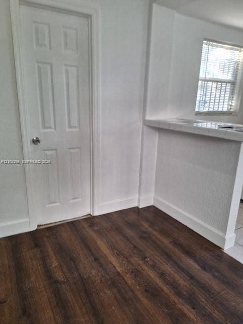 Wood-finish flooring with white baseboards and a paneled door