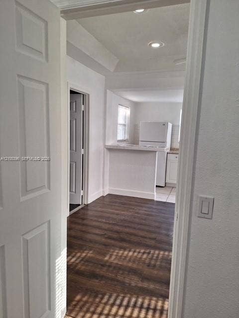 Wood-finish flooring, white paneled door, recessed lighting, and a kitchen pass-through with a countertop