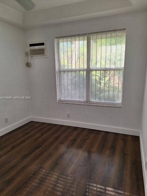 Recessed ceiling with an overhead fan, large window with horizontal blinds, integrated air conditioning unit, and wood-finish flooring