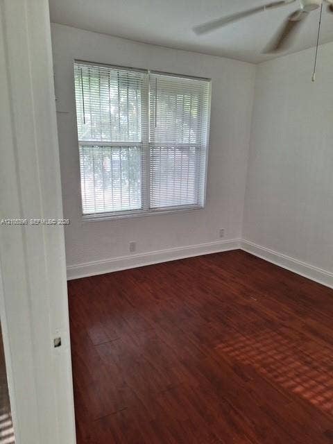 Wood-finish flooring, white walls, double window with horizontal blinds, and a ceiling fan