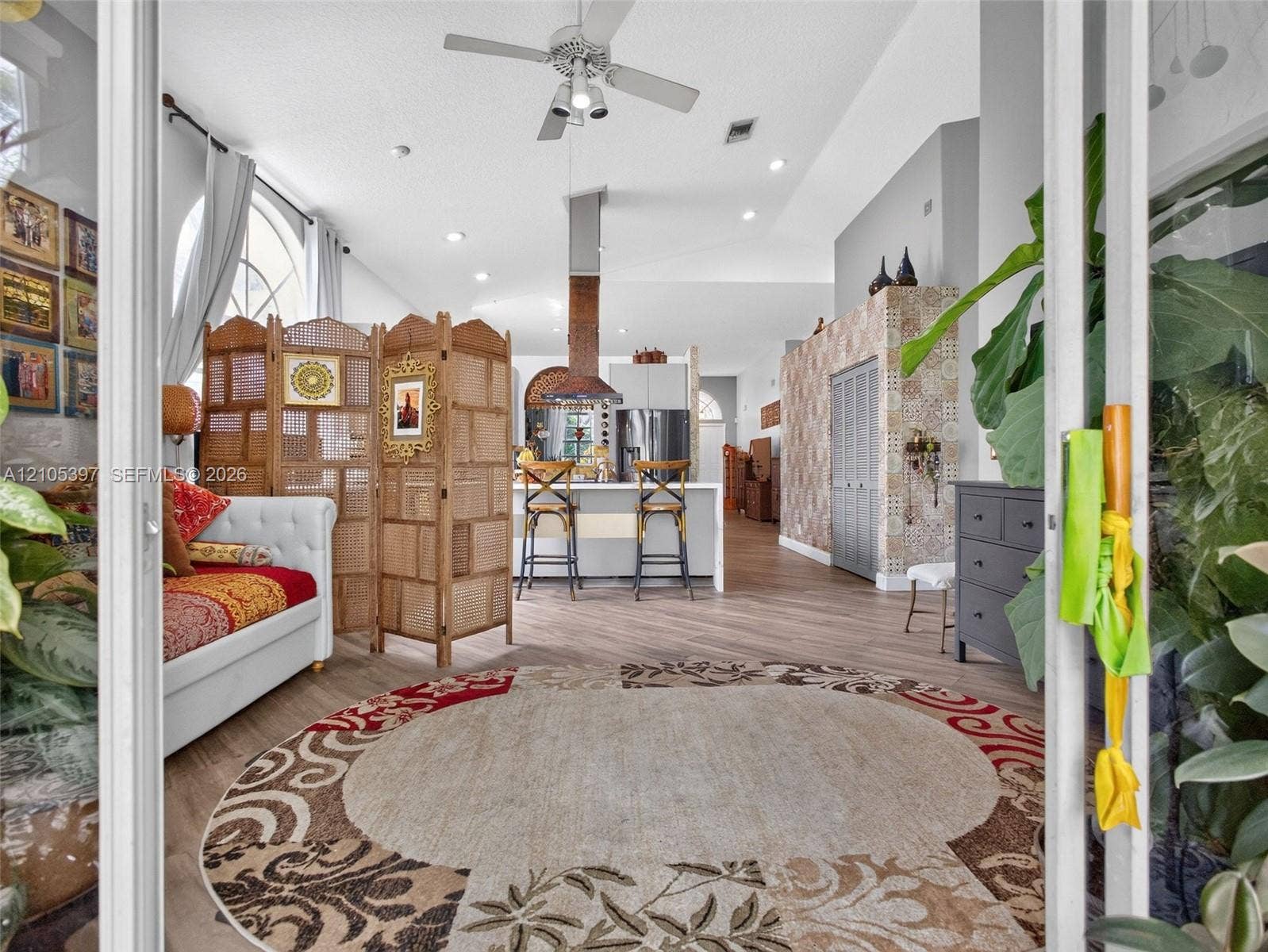 Vaulted ceilings, recessed lighting, ceiling fan, and decorative tile accent wall