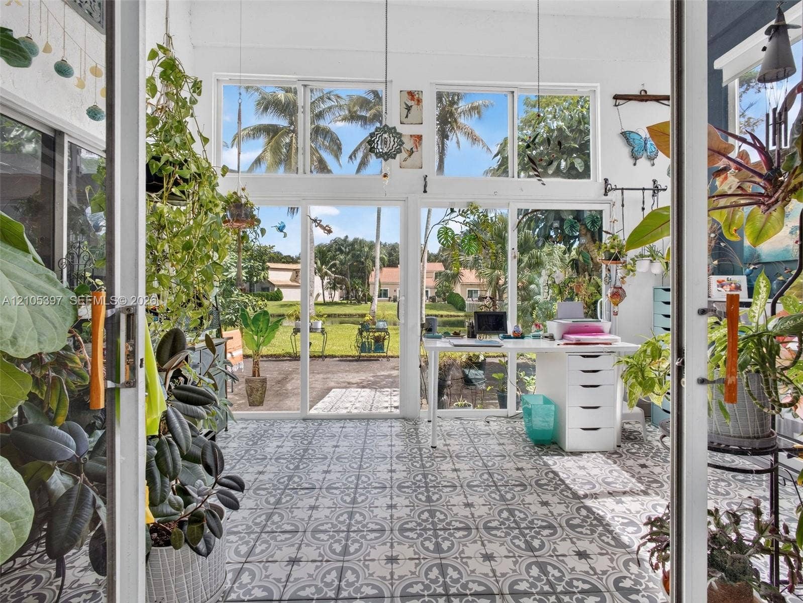 Sunroom featuring patterned ceramic floor tile, floor-to-ceiling windows, and sliding glass door access to the exterior. Ideal for arts and crafts nook, office, etc
