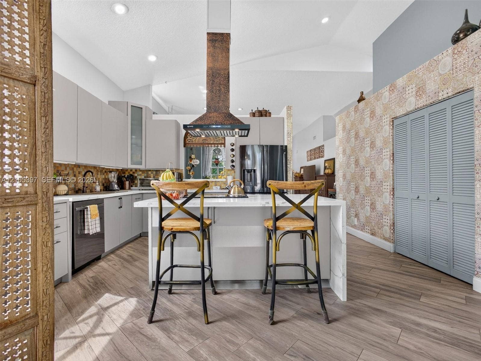 Kitchen featuring flat-panel cabinetry, a waterfall-edge center island, a hammered copper range hood, and porcelain wood-finish flooring
