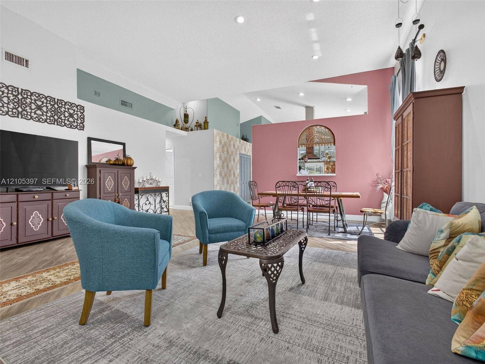 Open-concept floor plan featuring vaulted ceilings, recessed lighting, porcelain wood-finish flooring,