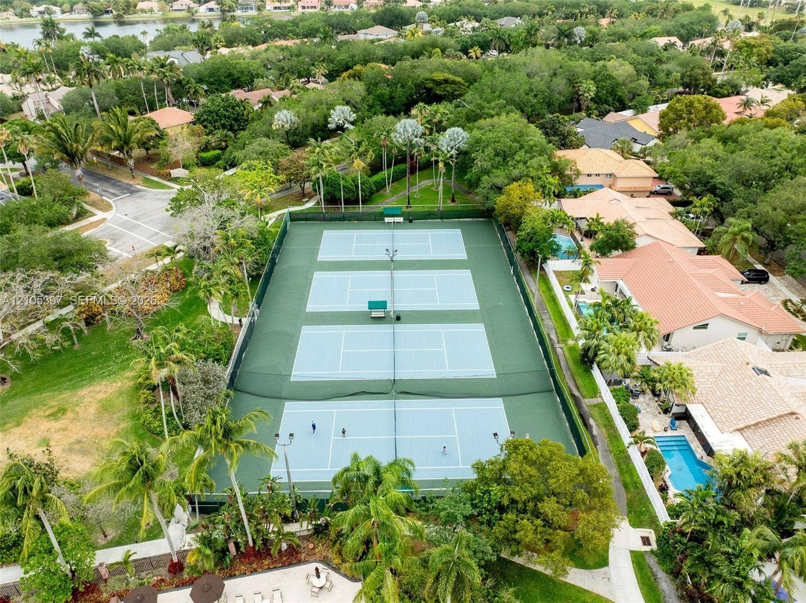 Fenced tennis court with high-mast lighting and perimeter screening