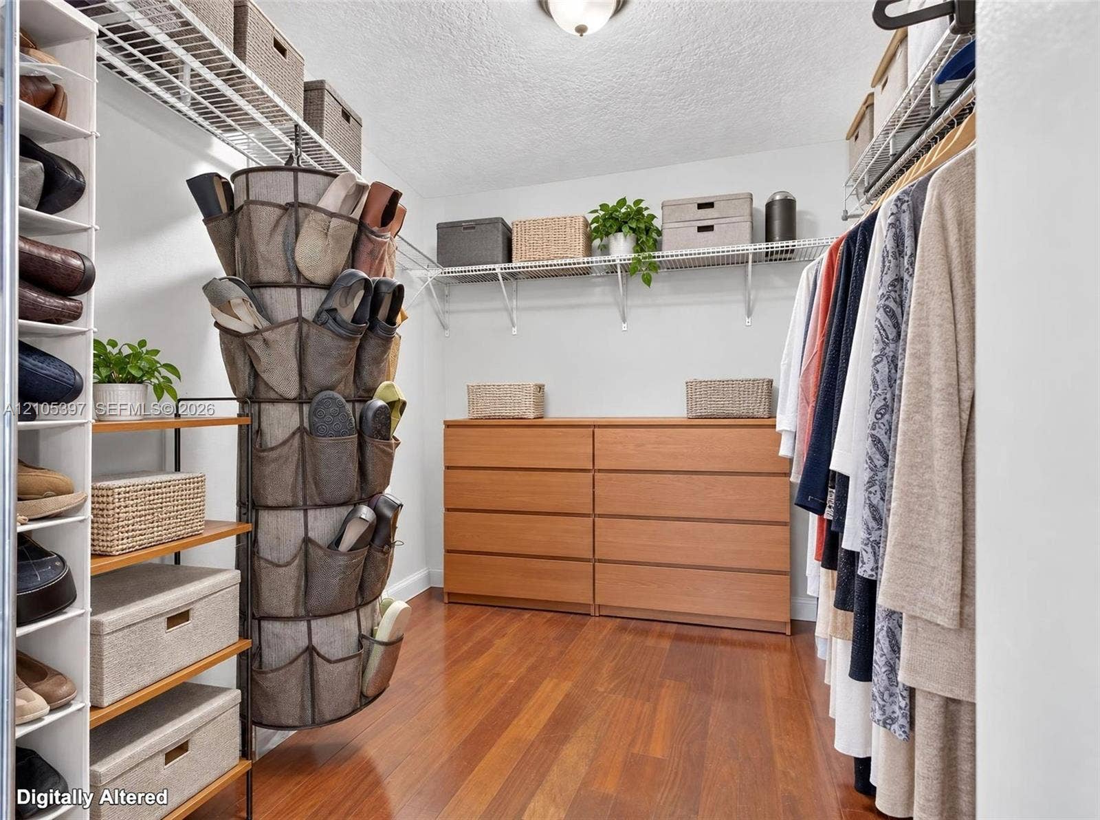 Walk-in closet featuring wood-finish flooring, multi-tier wire shelving, and built-in vertical storage towers