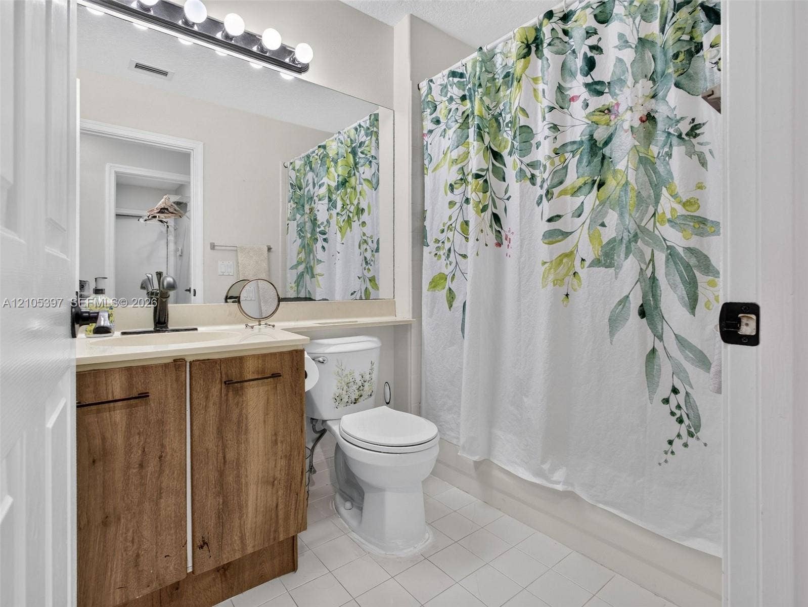Bathroom vanity with wood-finish cabinetry, countertop with integrated sink, full-width wall mirror