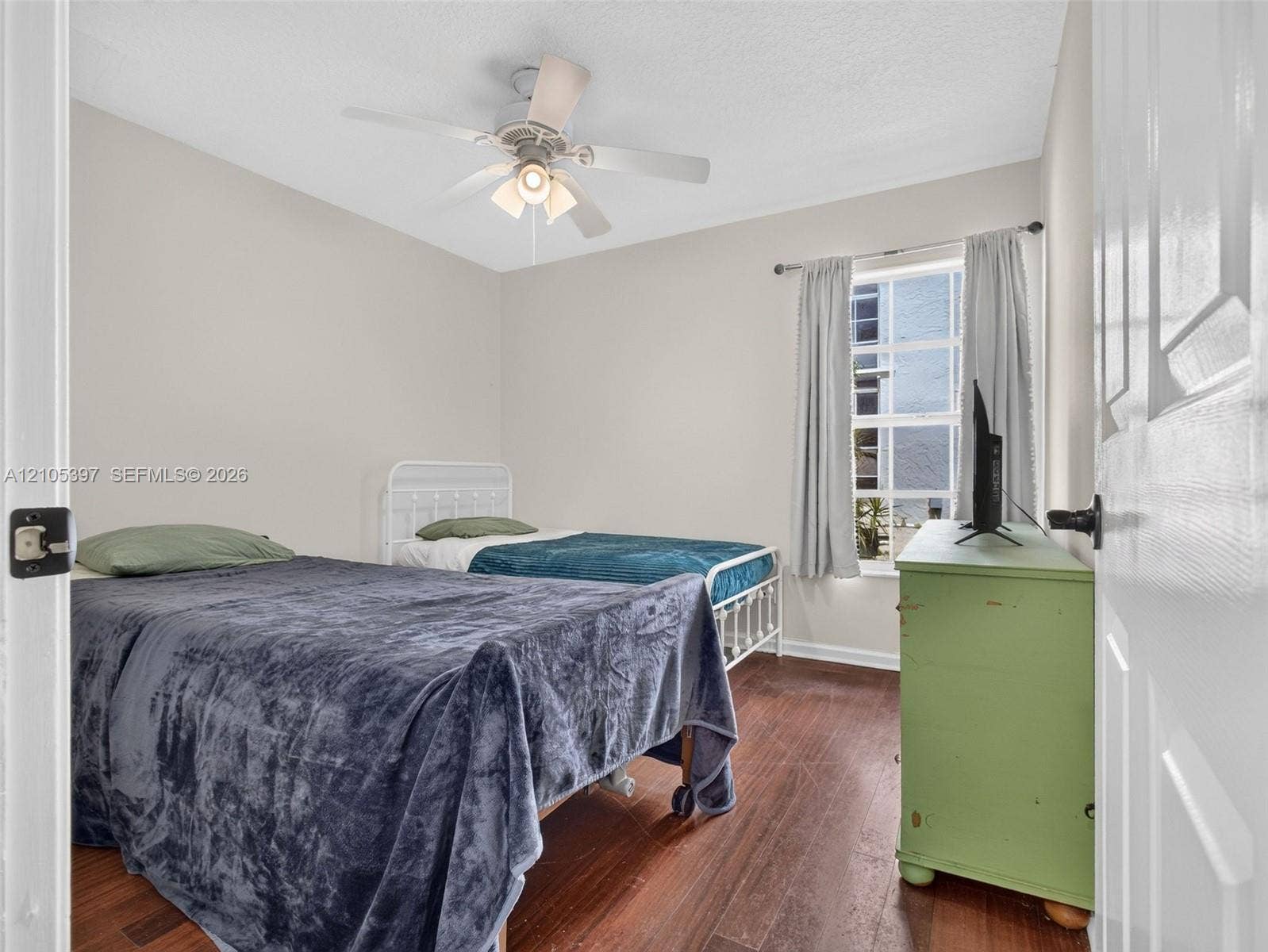 3rd bedroom featuring laminate flooring, a ceiling fan with integrated lighting, and a window with a curtain rod