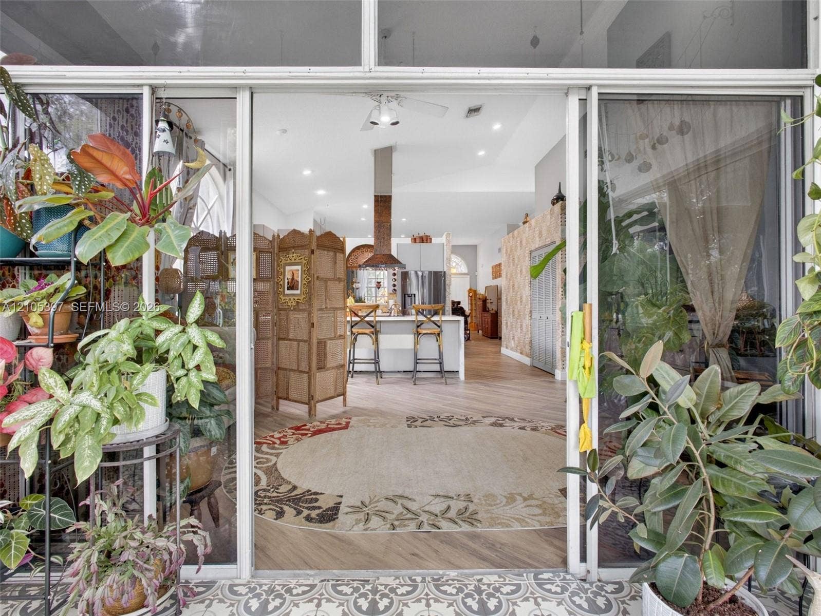 Florida room/enclosed patio featuring decorative patterned tile flooring and glass sliding doors leading to the family room