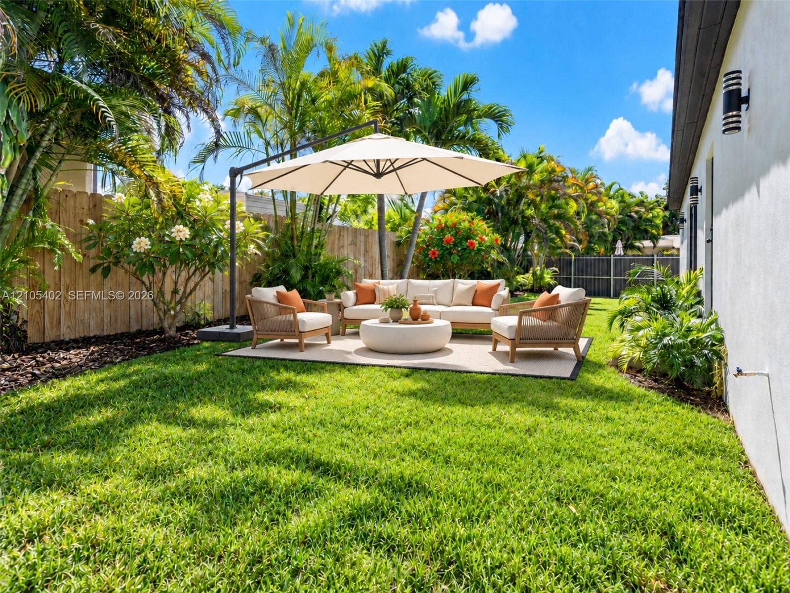 1911 SW 18th Avenue, Miami, FL 33145 Private backyard featuring a level grass lawn, mature tropical landscaping, and a wood privacy fence