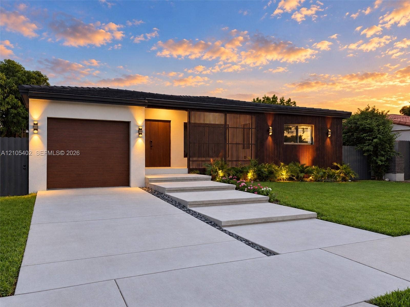 1911 SW 18th Avenue, Miami, FL 33145 Modern exterior featuring a combination of stucco and wood-finish cladding, single-car garage, integrated screen paneling, and concrete slab walkway with stone accent border