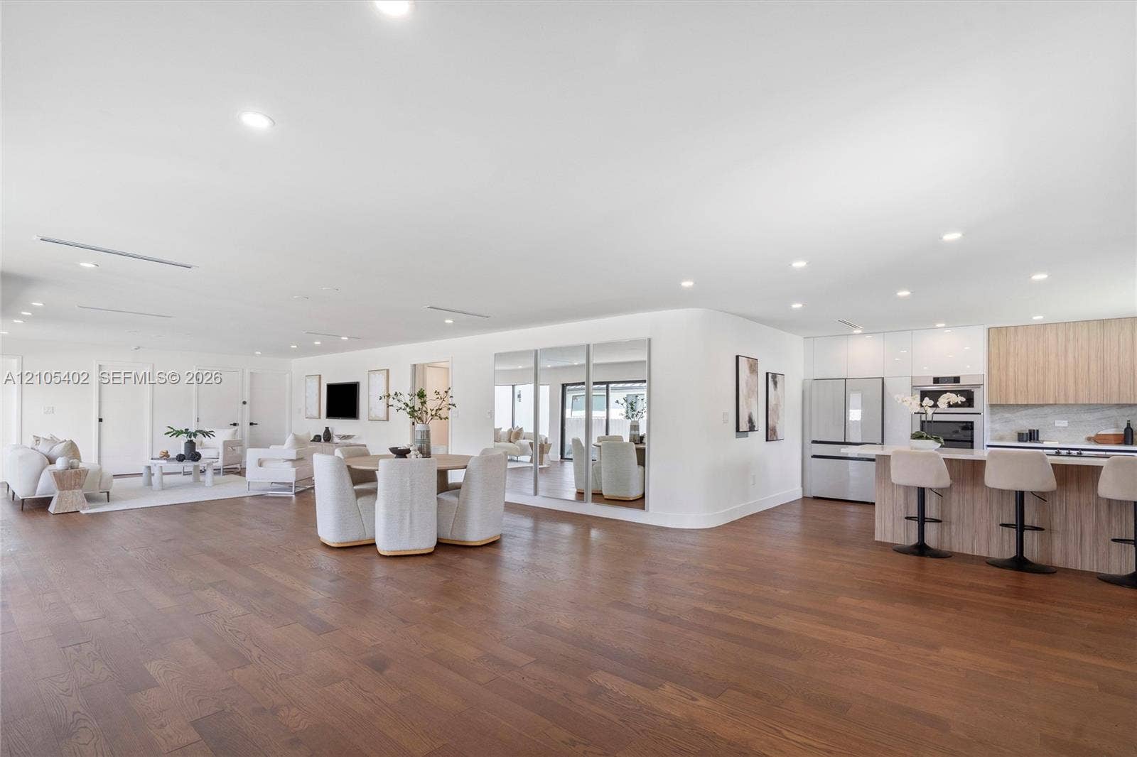 1911 SW 18th Avenue, Miami, FL 33145 Open-concept interior featuring wood-finish flooring, recessed lighting, a built-in mirrored wall, and a kitchen equipped with wood-finish cabinetry and a tiered island