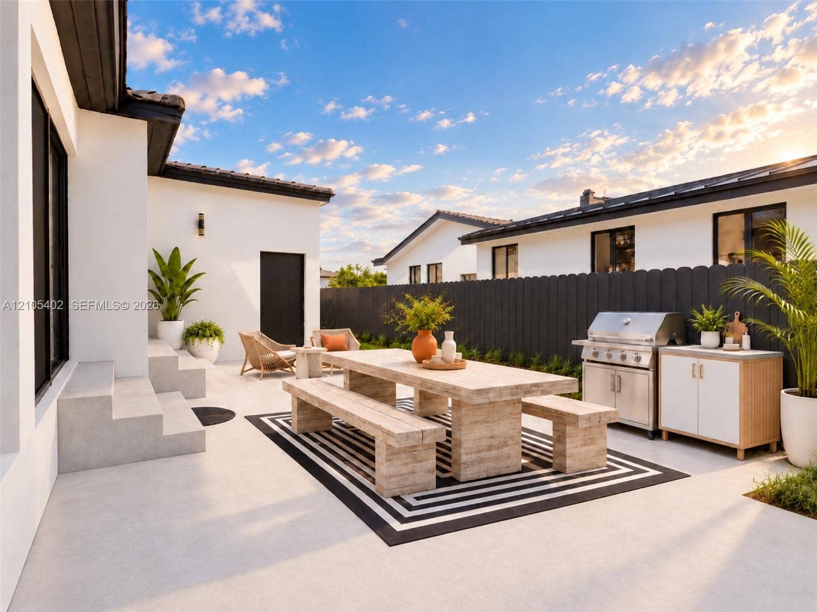 1911 SW 18th Avenue, Miami, FL 33145 Outdoor patio featuring smooth concrete hardscaping, a stainless steel built-in grill, stone-finish cabinetry, and dark vertical wood fencing