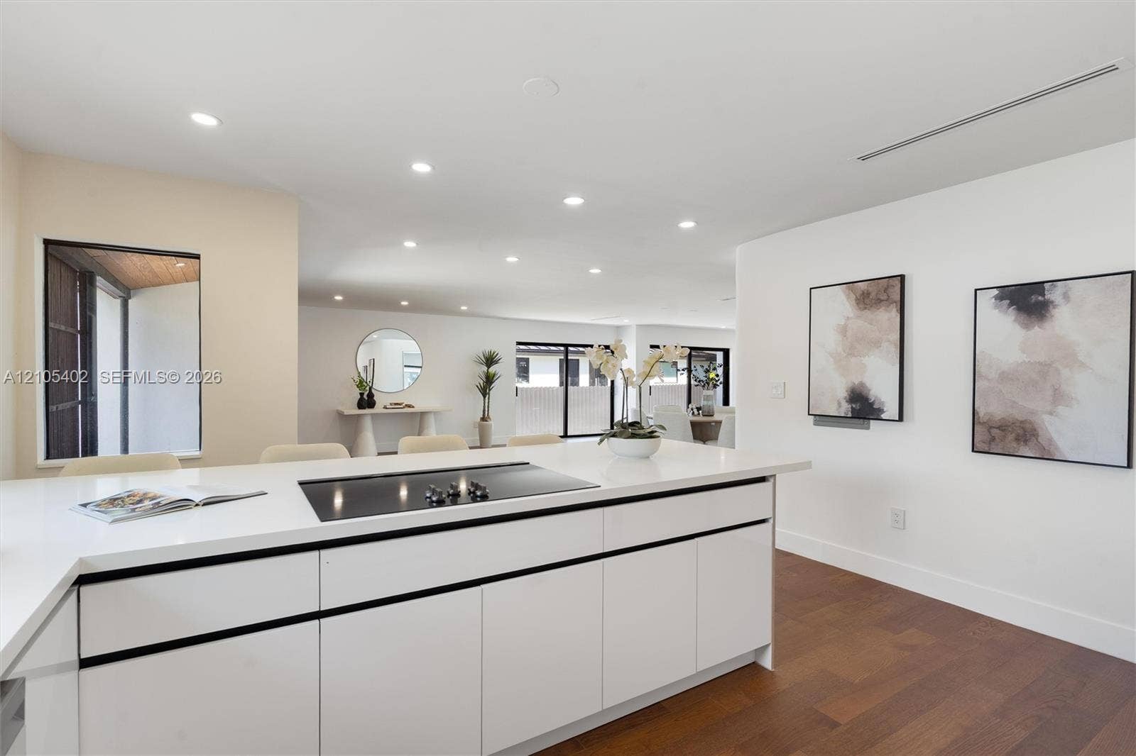1911 SW 18th Avenue, Miami, FL 33145 Kitchen island featuring white flat-panel cabinetry, a solid surface countertop, and an integrated cooktop, complemented by recessed lighting and wood-finish flooring