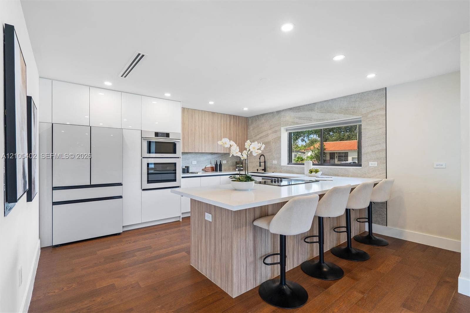 1911 SW 18th Avenue, Miami, FL 33145 Kitchen featuring flat-panel cabinetry, a central island with a solid surface countertop, wood-finish flooring, integrated wall ovens, and a stone-style tile backsplash