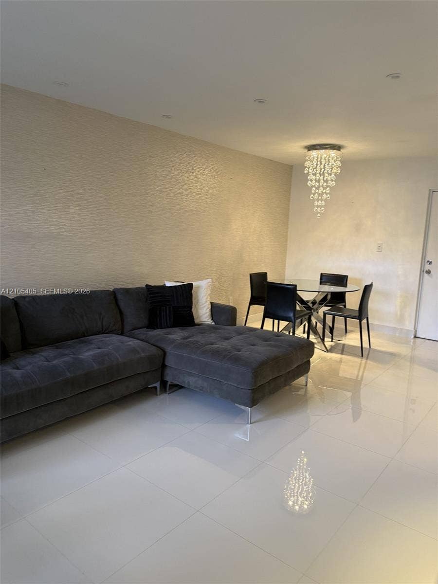 17570 Atlantic Boulevard, #119, Sunny Isles Beach, FL 33160 Recessed ceiling lights, textured accent wall, polished tile flooring, and a crystal chandelier