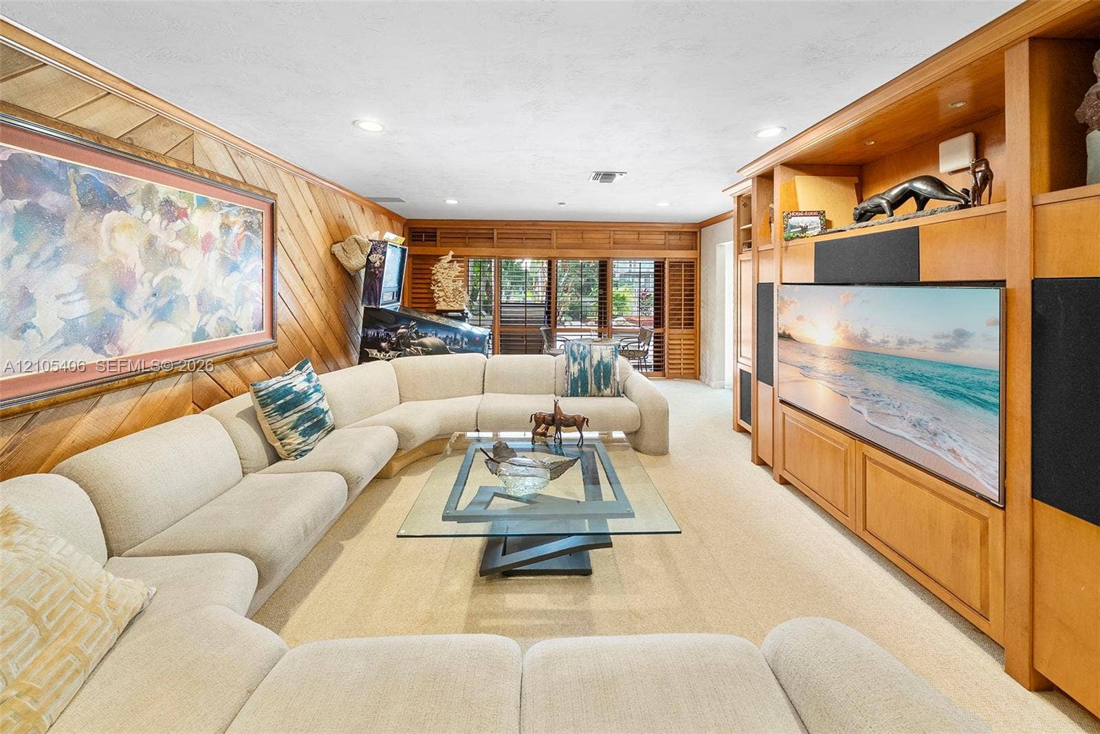 Wood-paneled wall, recessed lighting, built-in media center, plantation shutters, and light-toned carpet