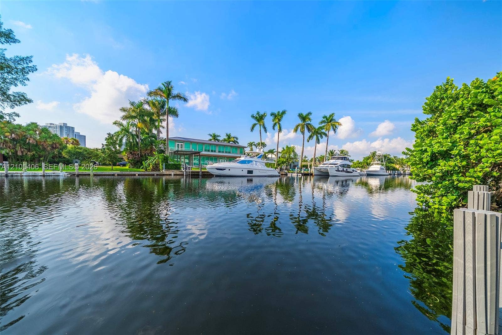 Waterfront property featuring a private dock, mature palm trees, lush landscaping, and direct canal access