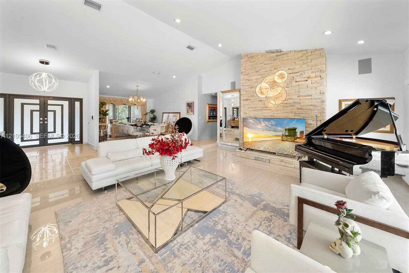 Vaulted ceiling, recessed lighting, stone accent wall, double entry doors, and polished flooring