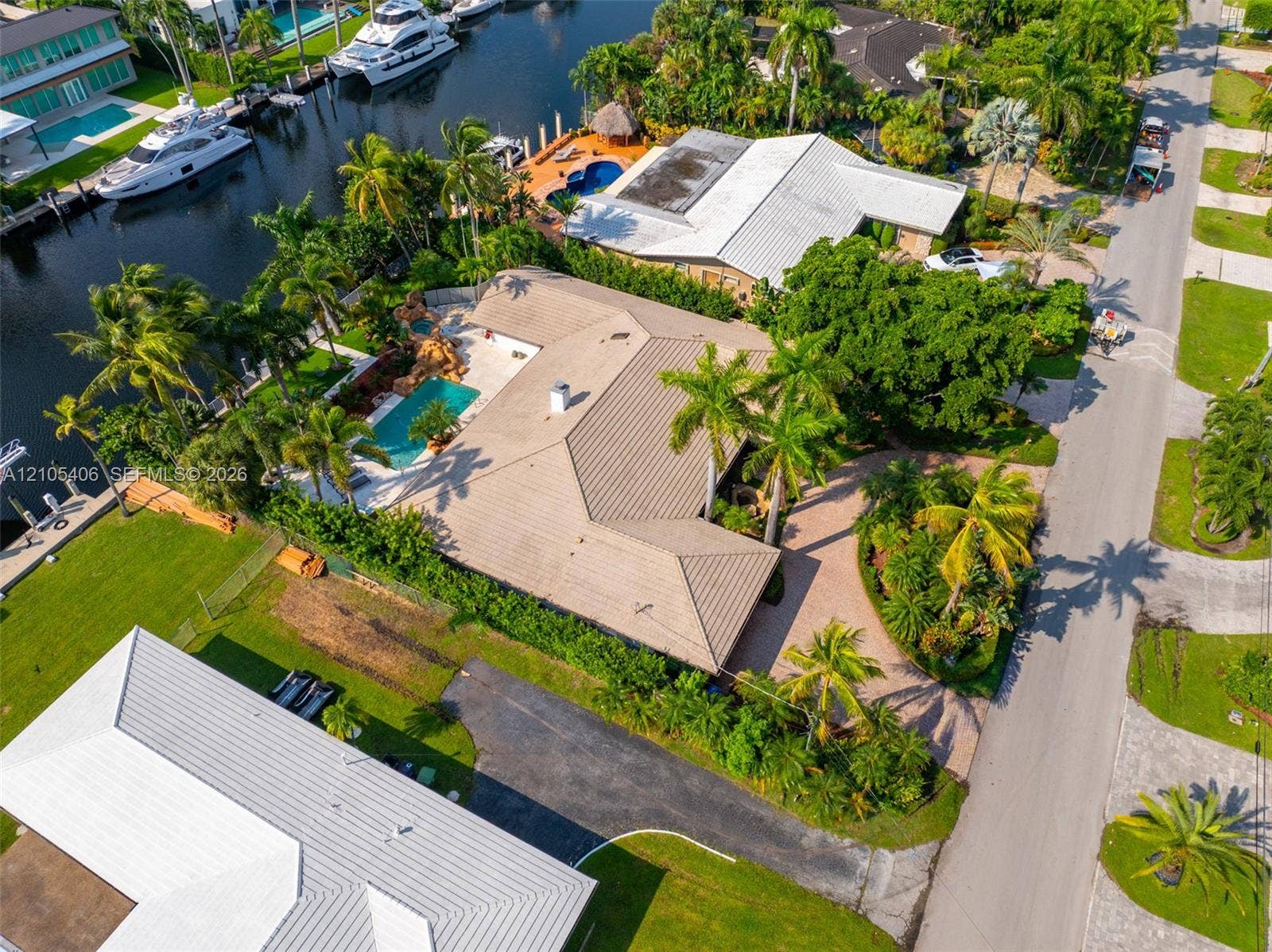 Waterfront property featuring a private boat dock, extensive landscaping, swimming pool, and concrete tile roofing
