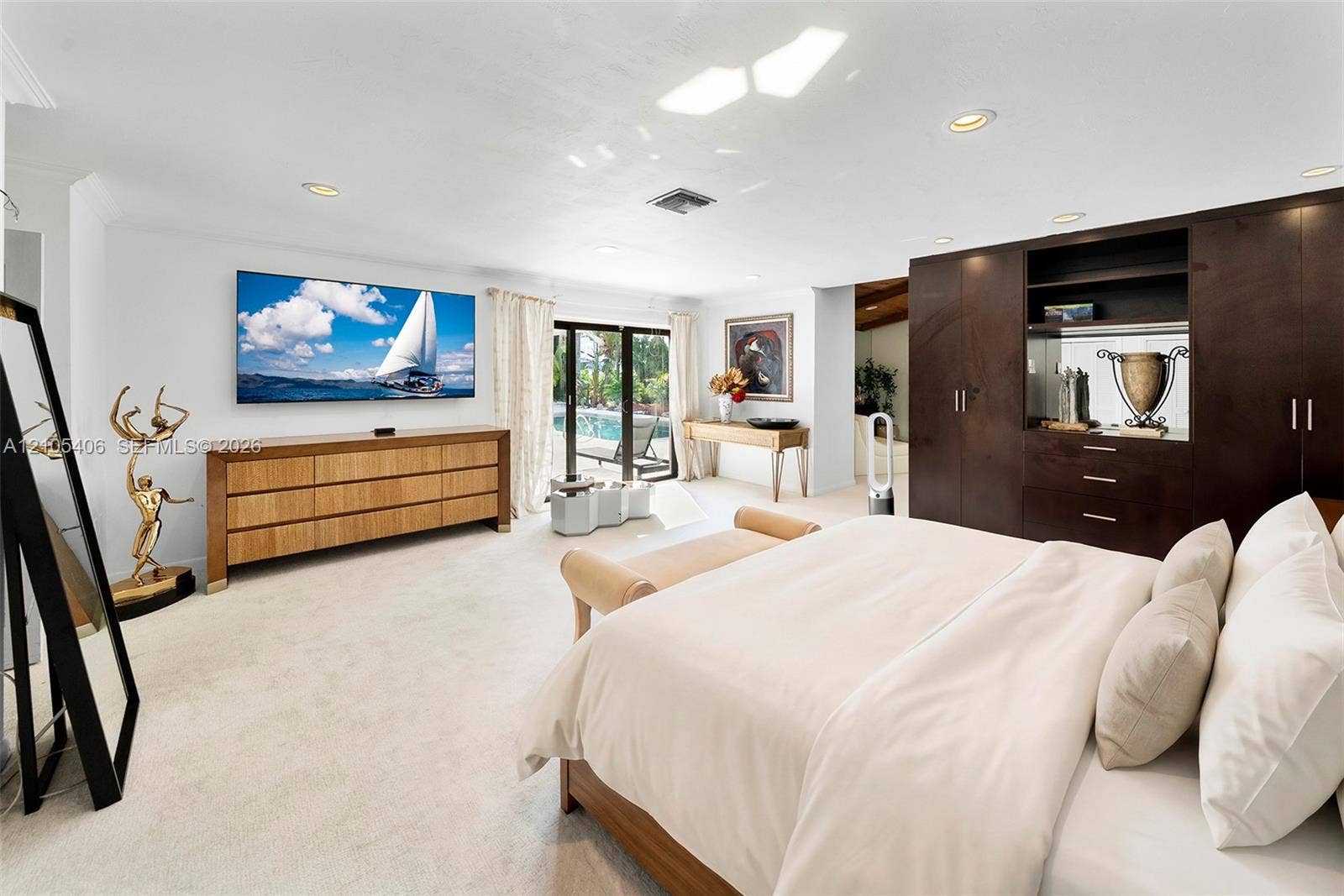 Recessed lighting, light-toned carpeting, built-in dark wood cabinetry, glass sliding doors, and white walls