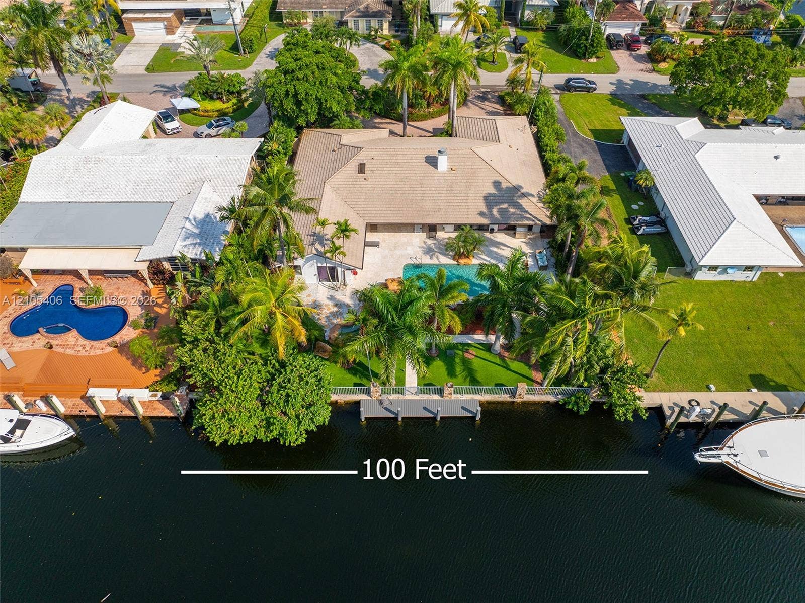 Waterfront property featuring a private boat dock, in-ground swimming pool, and extensive paved patio