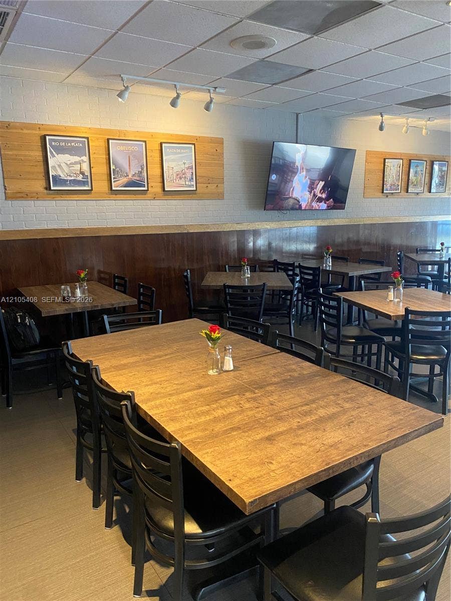 Wood-finish tabletops complemented by black chairs, track lighting, and a drop ceiling
