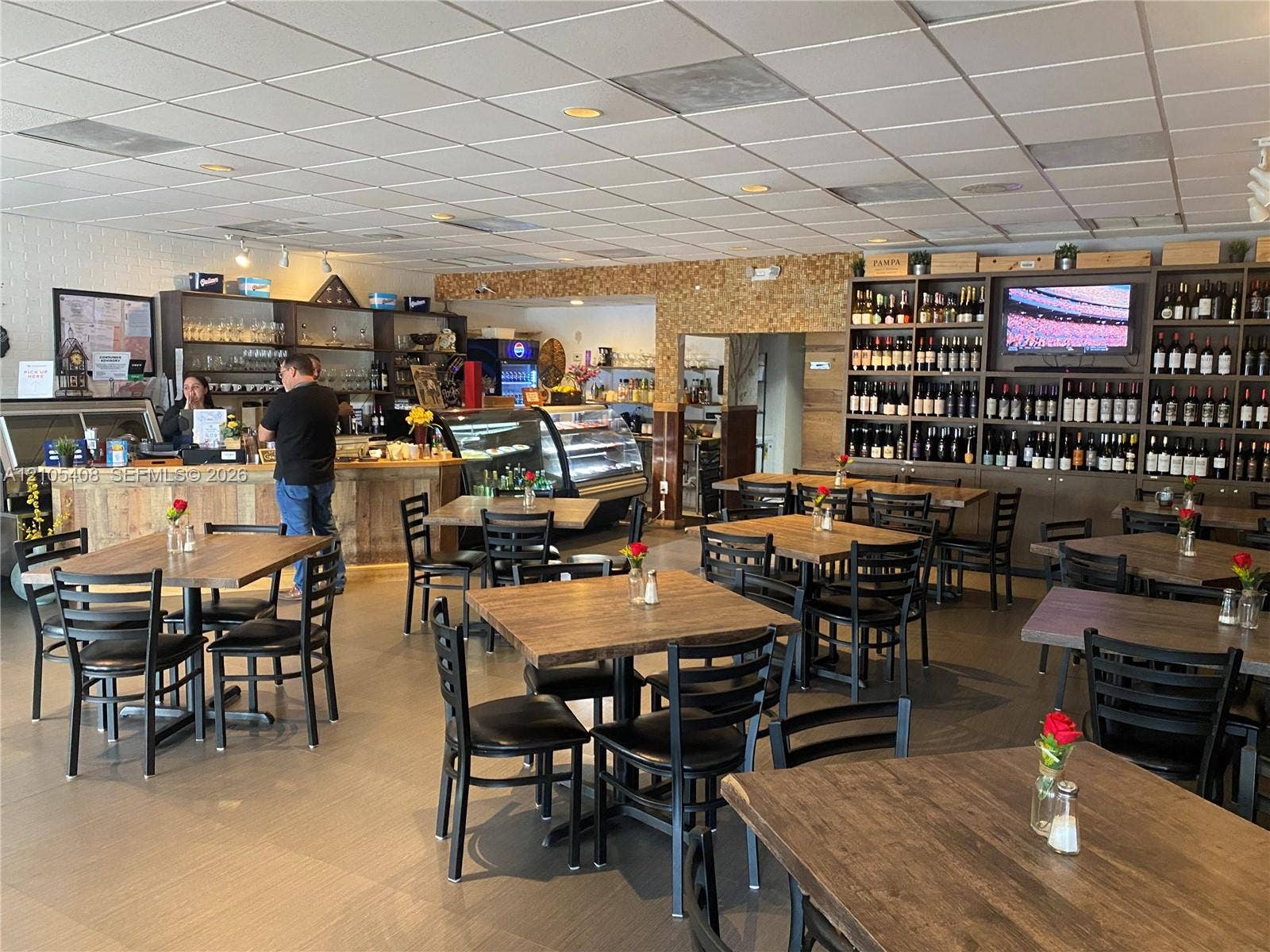 Spacious dining area with multiple tables and chairs, a service counter, and extensive wall-mounted shelving