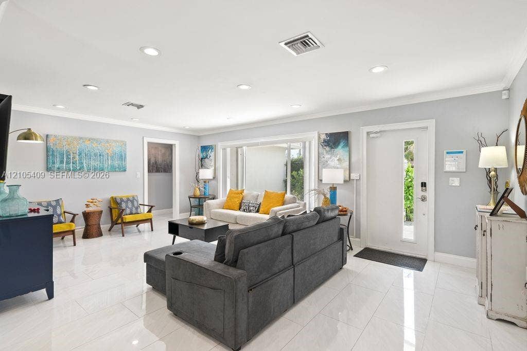 Recessed lighting illuminates the living space, featuring white tile flooring and a light gray wall color