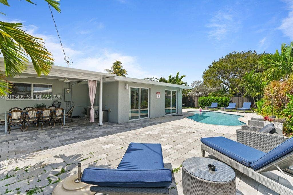 Outdoor living area featuring a swimming pool, paved patio, covered patio, and lush landscaping