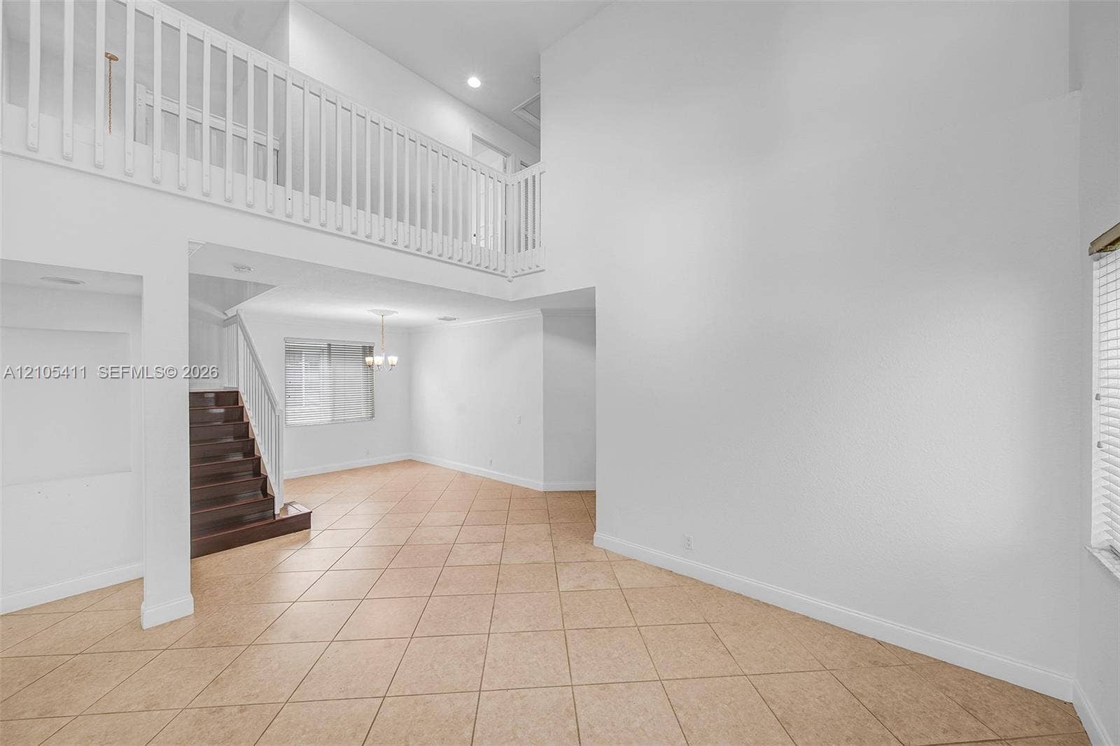 Two-story interior featuring a second-level open railing, recessed lighting, and a chandelier-style fixture