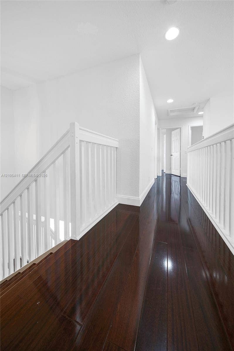Dark wood-finish flooring with white baseboards and recessed lighting