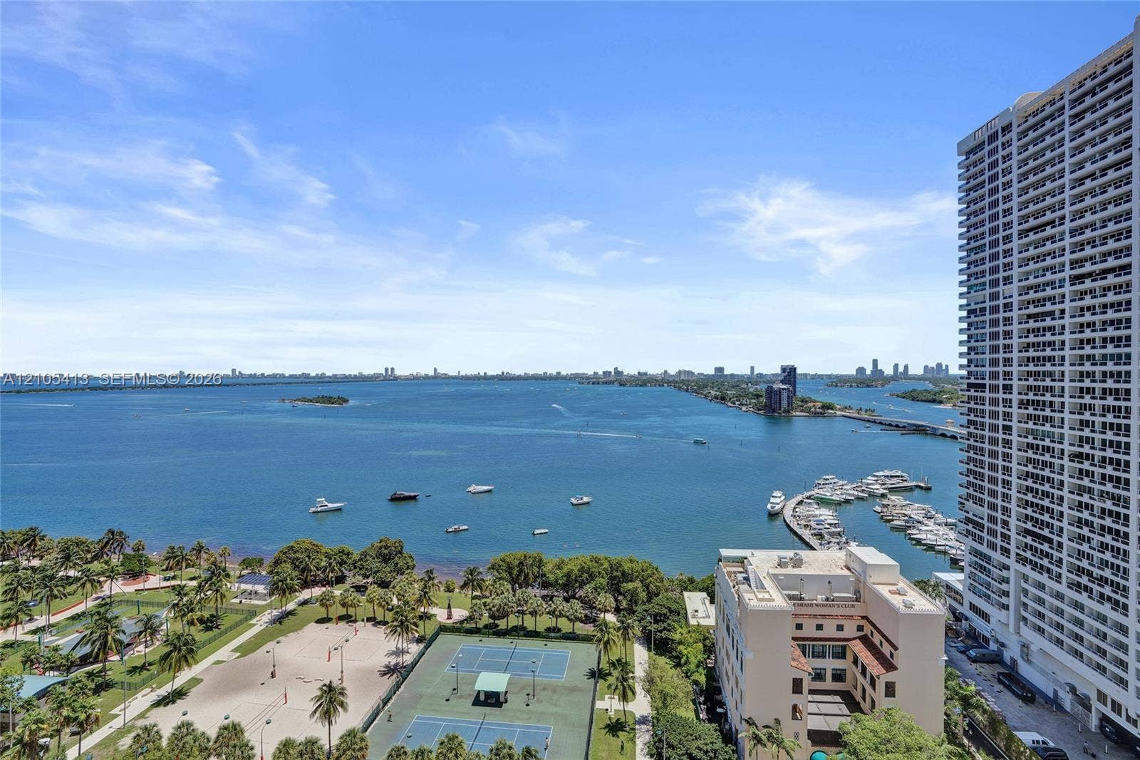 Expansive water frontage with marina access, city skyline, tennis courts, and mature landscaping
