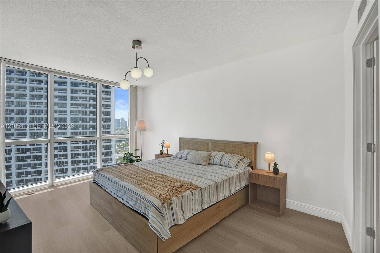 Expansive window wall with city backdrop, wood-finish flooring, and a contemporary ceiling fixture