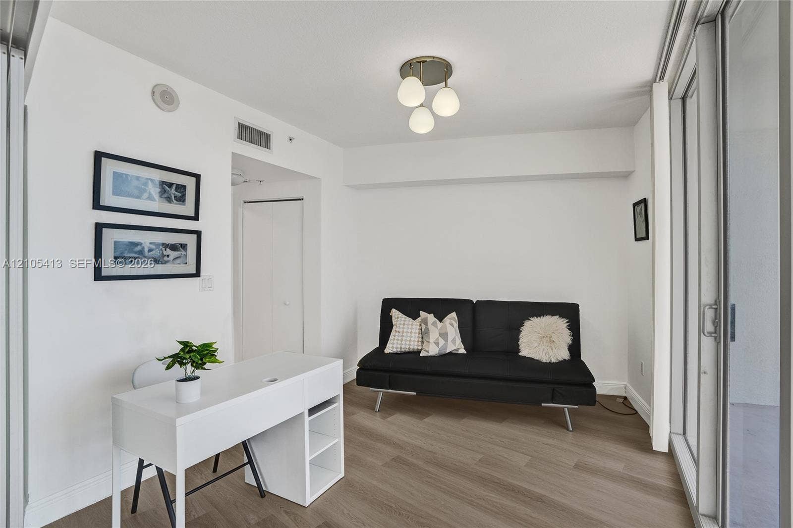 Light wood-finish flooring, white walls, and a contemporary ceiling light fixture