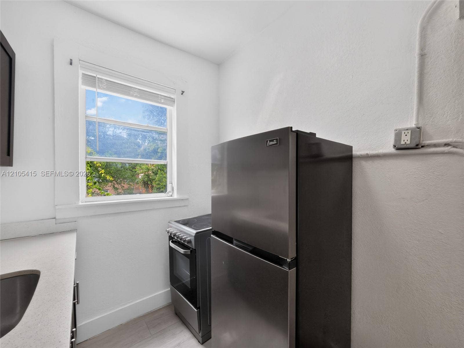 967 SW 5th Street, #11, Miami, Miami, FL 33130 Stainless steel refrigerator and freestanding range, neutral solid-surface countertop, and window with natural illumination